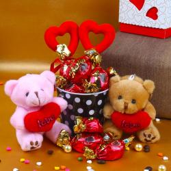 Send Valentines Day Gift Valentine Special Hamper of Couple Teddy holding a heart with Merlin Chocolates To Indore